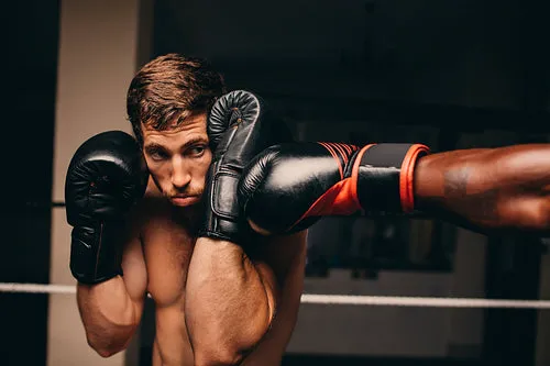 Boxing athlete blocking a punch to his jaw